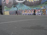 the painted elephant is near a basketball court with a man standing outside of it's door