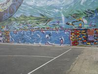 the painted elephant is near a basketball court with a man standing outside of it's door