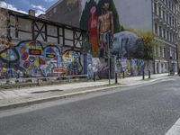 the street in front of the graffiti covered building is empty and empty, but has two rows