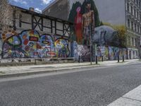 the street in front of the graffiti covered building is empty and empty, but has two rows