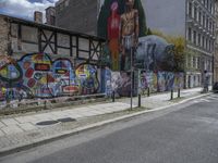 the street in front of the graffiti covered building is empty and empty, but has two rows