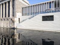 an empty pool next to a large building with a staircase and stairs on the side of it