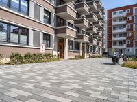 an apartment complex with a small walkway and brick patio area leading into the building facade