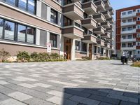 an apartment complex with a small walkway and brick patio area leading into the building facade