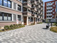 an apartment complex with a small walkway and brick patio area leading into the building facade