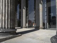 a picture of pillars and one pillar next to a building with many windows and people outside it