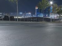 an empty city street with lights shining on the buildings at night with no people on the pavement