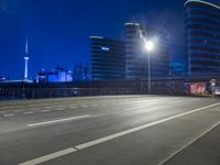 city streets at night with lights shining over the top of buildings and a long highway