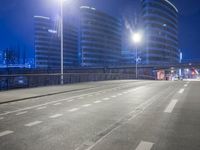 city streets at night with lights shining over the top of buildings and a long highway