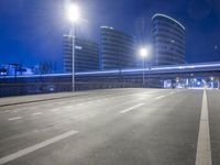 city streets at night with lights shining over the top of buildings and a long highway