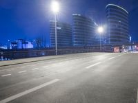 city streets at night with lights shining over the top of buildings and a long highway