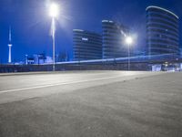 city streets at night with lights shining over the top of buildings and a long highway