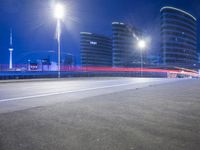city streets at night with lights shining over the top of buildings and a long highway