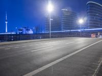 city streets at night with lights shining over the top of buildings and a long highway