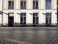 a couple of tables in the middle of a road next to a building with windows