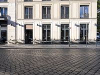 a couple of tables in the middle of a road next to a building with windows