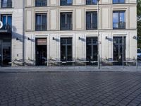 a couple of tables in the middle of a road next to a building with windows