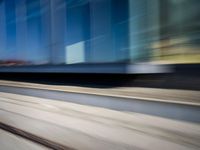 a train passing by some bushes and trees on tracks during the day, while a person holds a phone to her ear