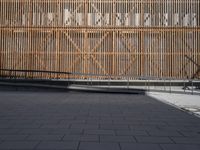 a man skateboards on the side of an empty sidewalk next to a bamboo wall