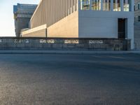 empty street lined with cement buildings next to a tall building with a staircase up to it