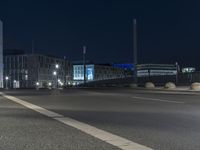 large building on the street with lights in front and other buildings nearby at night with no one moving