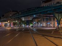 the empty street is filled with people walking and biking under an overpass at night