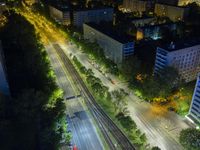 an aerial view of a city at night, with the road and tracks going through the city