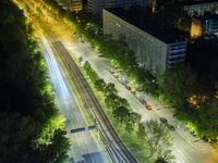 an aerial view of a city at night, with the road and tracks going through the city