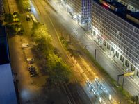 an aerial view of a city at night, with the road and tracks going through the city