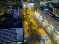 an aerial view of a city at night, with the road and tracks going through the city