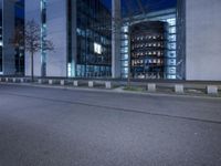 an empty street near a building with some lights on and a street sign on it