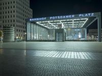 a night time picture of a large building at the bank of potsdam plaza, with light streaming through its glass facade