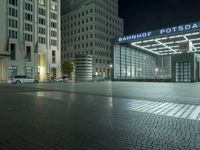 a night time picture of a large building at the bank of potsdam plaza, with light streaming through its glass facade