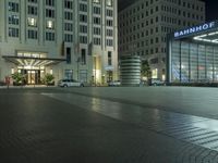 a night time picture of a large building at the bank of potsdam plaza, with light streaming through its glass facade