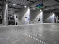 parking garage floor with silver tiles and circular holes at the entrance to the building and signs