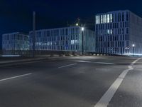 large building on the street with lights in front and other buildings nearby at night with no one moving