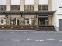 an empty building with signs on the street and people on bikes in traffic passing by