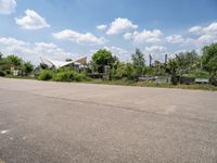 the empty parking lot in front of the small residential house and lots of greenery