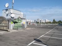 a bus stop is in the middle of a parking lot, where there are several satellite antennas on the side