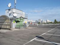 a bus stop is in the middle of a parking lot, where there are several satellite antennas on the side