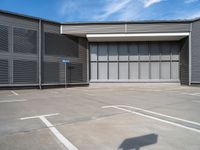 a small parking space in front of a grey building with multiple windows and signs hanging on the side of it