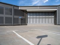 a small parking space in front of a grey building with multiple windows and signs hanging on the side of it