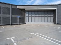 a small parking space in front of a grey building with multiple windows and signs hanging on the side of it