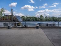 the benches are next to a lake on a sunny day and look out at clouds