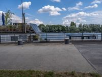 the benches are next to a lake on a sunny day and look out at clouds