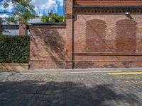 a long empty brick street with tall buildings in the background on a sunny day with some people walking around