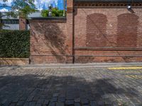 a long empty brick street with tall buildings in the background on a sunny day with some people walking around