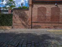 a long empty brick street with tall buildings in the background on a sunny day with some people walking around