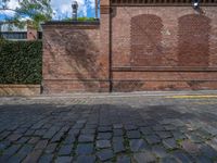 a long empty brick street with tall buildings in the background on a sunny day with some people walking around