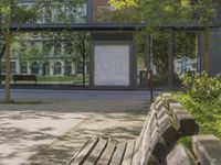 benches in front of a building with trees on it and glass doors to a building